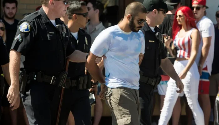 A man is lead away after getting arrested in front of Mutt Lynch's on the Balboa Peninsula in Newport Beach